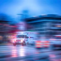 an ambulance racing through the rain on a stormy night with motion blur (NO SHARP FOCUS DUE TO RAIN) with reflections in the road